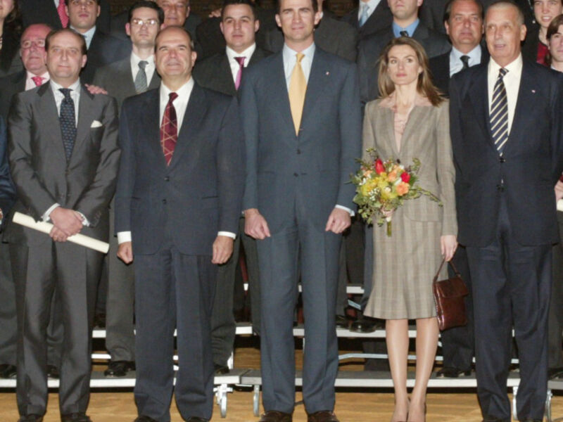 Gruppo formale in abito e giacca, con una donna in vestito e mazzo di fiori.