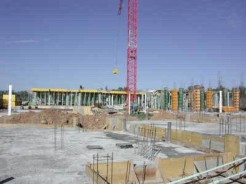 Estadio en construcción con estructuras de hormigón y una grúa en el centro.