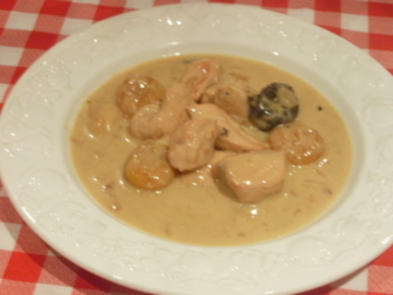 Un plato de sopa de pollo con champiñones y una cucharada de salsa de tomate en el centro. El plato está servido en una mesa con una mantel de cuadros rojos y blancos.