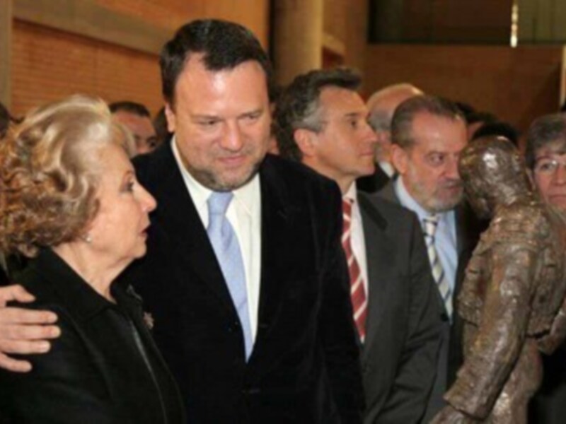 Celebración en un evento formal con personas vestidas de gala y una escultura al fondo.