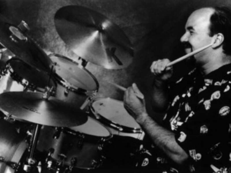 Joven tocando batería con entusiasmo, expresando su pasión por la música.