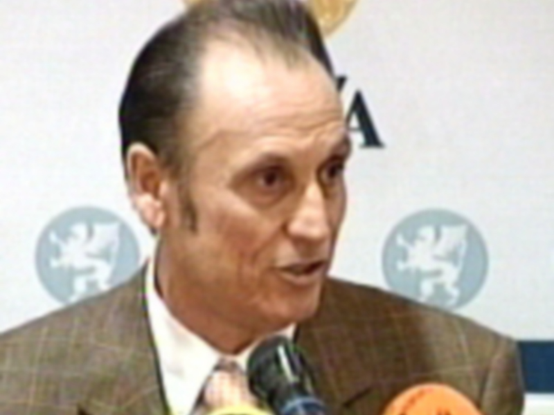 Persona hablando en una conferencia de prensa con micrófonos en frente.