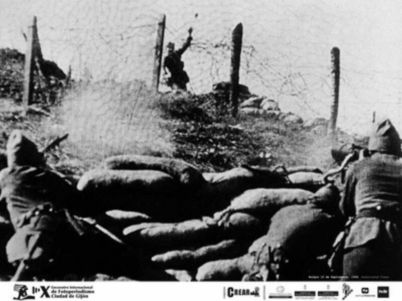 Soldados en una trinchera durante la Primera Guerra Mundial, con una figura levantada en el fondo, posiblemente celebrando o señalando.