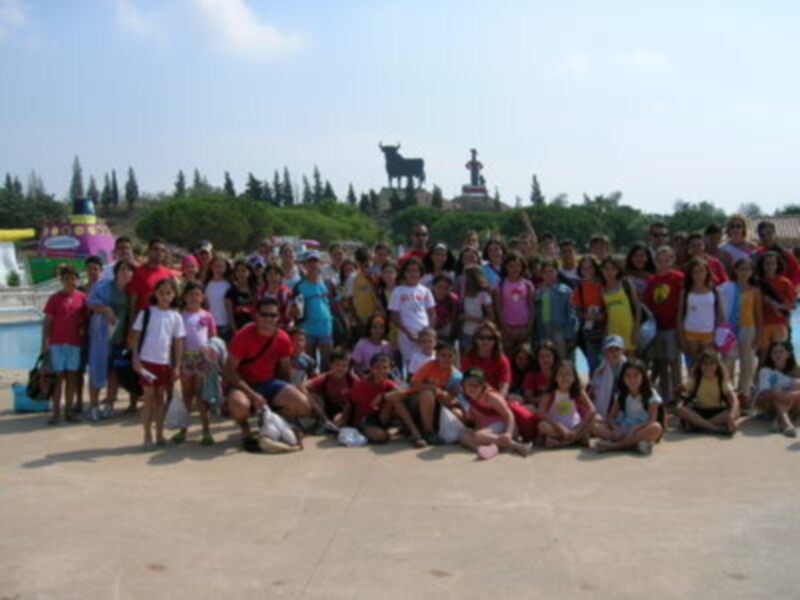 Grupo de personas en una escena histórica con un monumento en el fondo.