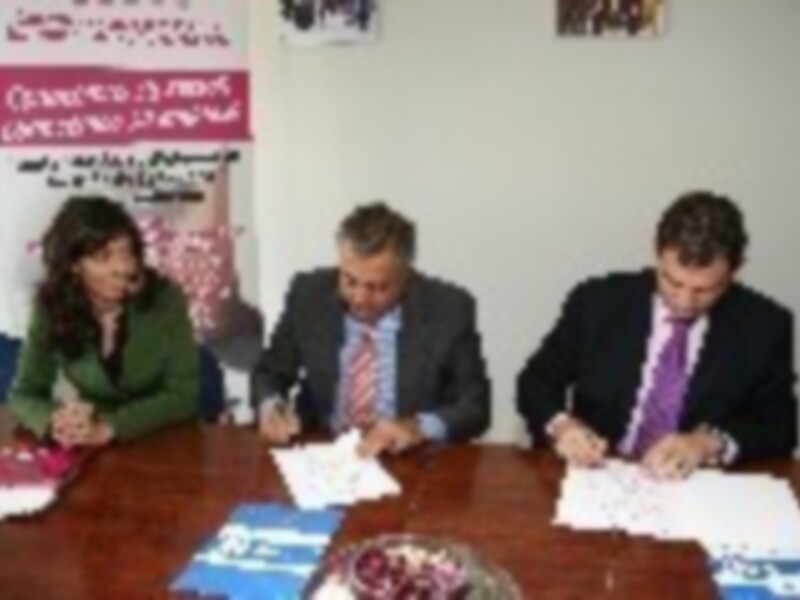 Reunión de negocios en una oficina, personas firmando documentos en una mesa.