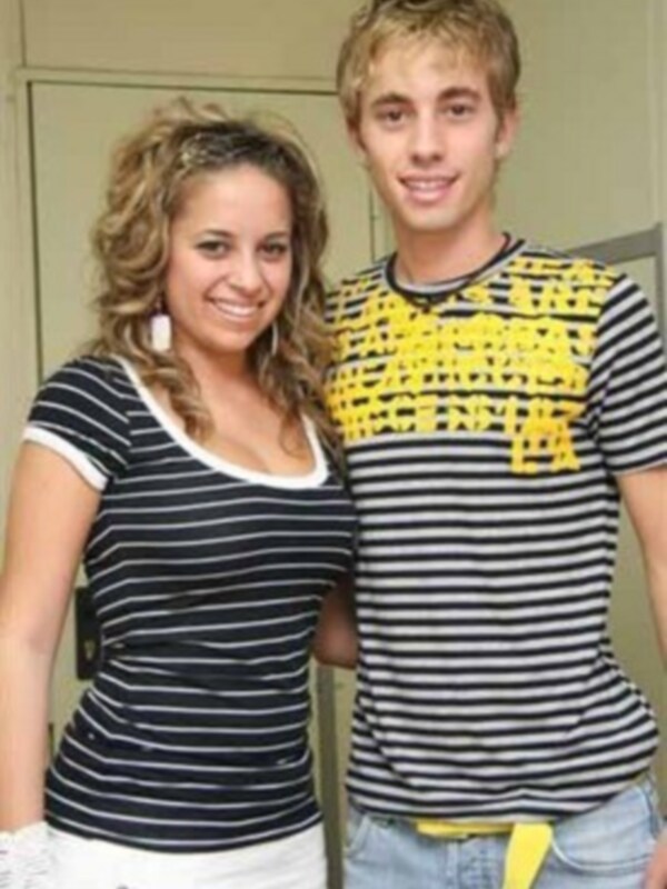 Dos jóvenes posando juntos, uno con una camiseta a rayas y el otro con una camiseta con letras amarillas.