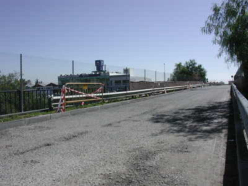 Puente con valla de seguridad y edificio en el fondo.