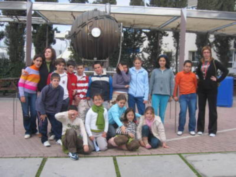 Grupo de niños y niñas posando frente a un gran tambor en una escuela.