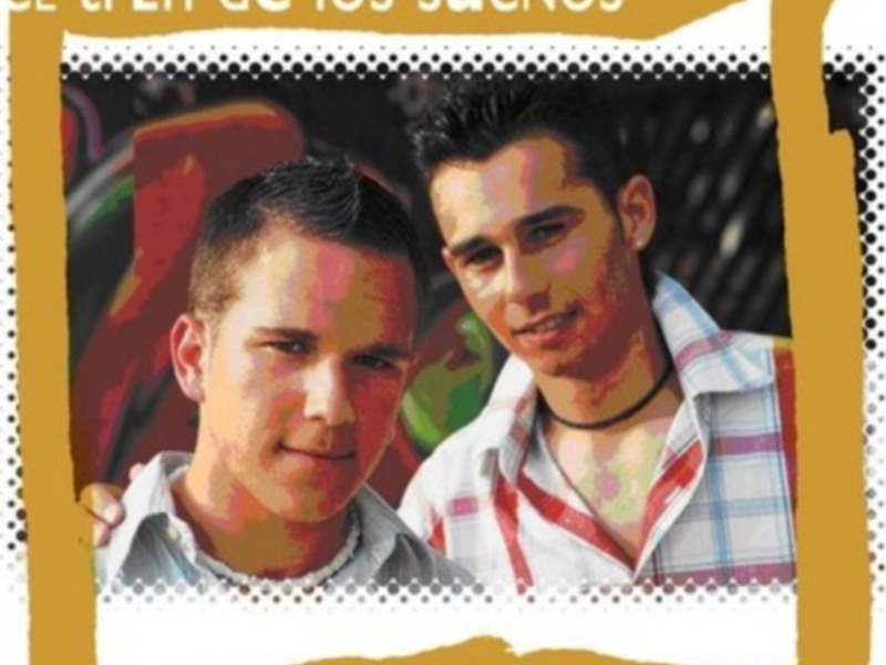 Dos jóvenes sonrientes, uno con una camisa blanca y el otro con una camisa con rayas rojas y blancas, con un fondo de pintura en tonos rojos y amarillos. El texto en la imagen dice 'El tren de los sueños' y 'Tu amor primero'.