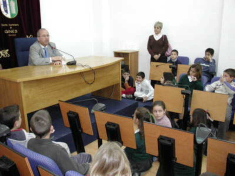 Un profesor dirige una clase en un aula con estudiantes sentados en mesas individuales.