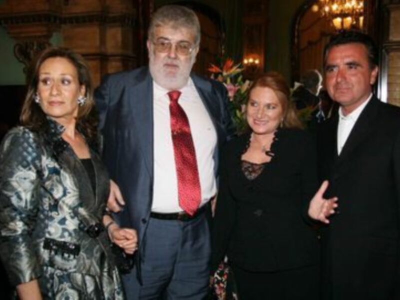 Grupo de personas en trajes y vestidos formales en un evento social.