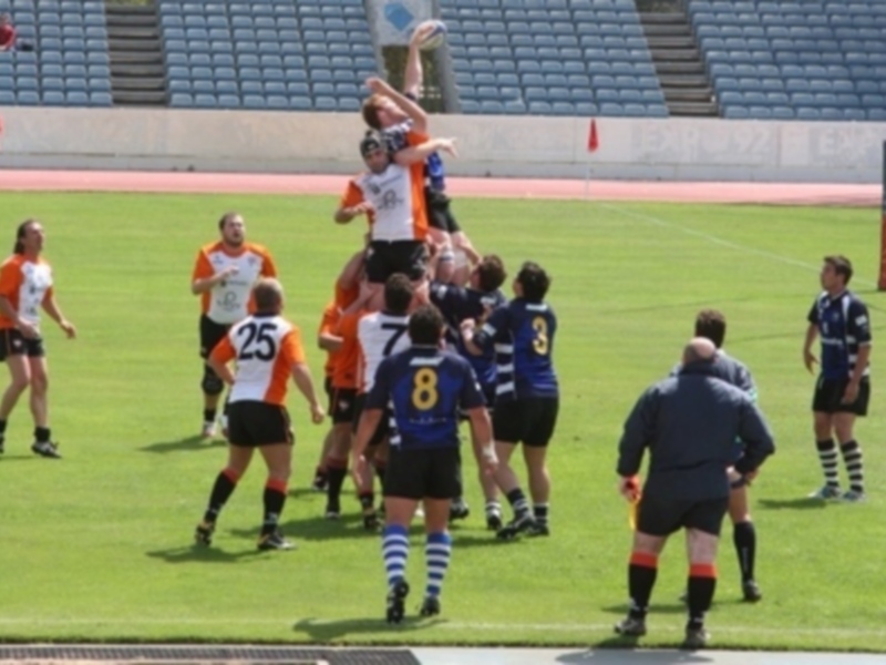 Jugadores de rugby compiten por el balón en un scrum durante un partido en un estadio vacío.