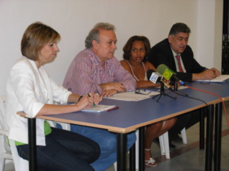 Conferencia de prensa con cuatro participantes sentados en una mesa con micrófonos y documentos.