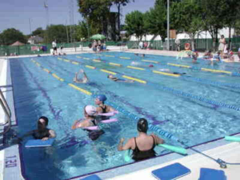 Clases de natación en una piscina al aire libre con nadadores aprendiendo técnicas de natación.