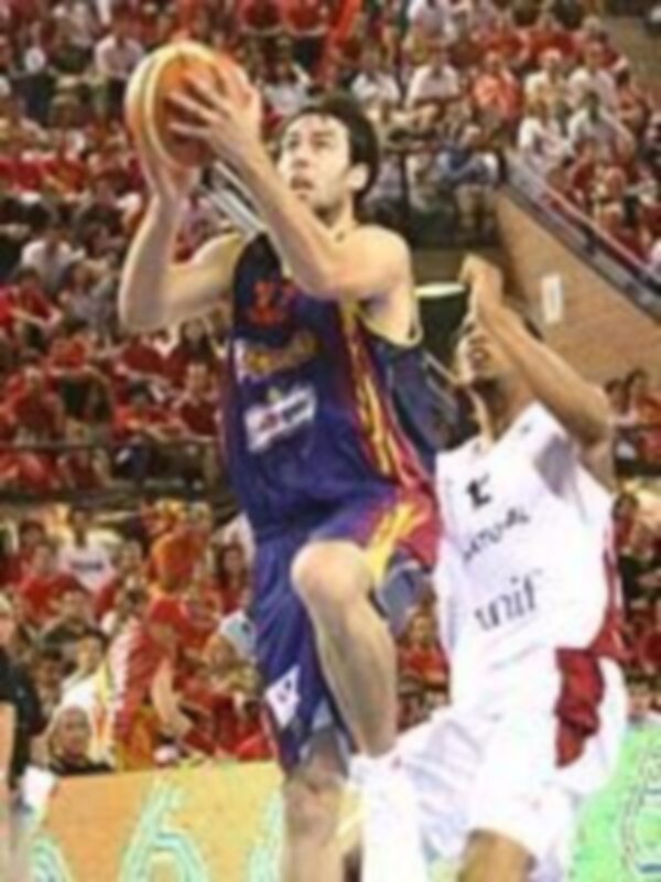 Jugador en acción durante un partido de baloncesto, lanzando el balón en un partido lleno de público.