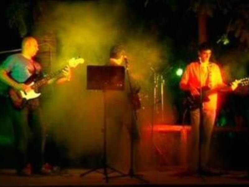 Banda tocando en vivo con luces de colores y humo en el escenario.