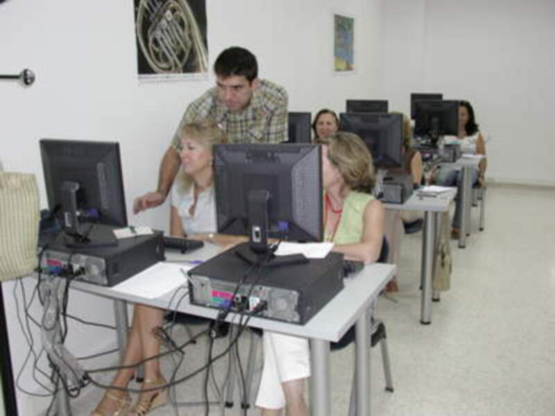 Un grupo de personas en una clase de informática, trabajando con computadoras y aprendiendo.