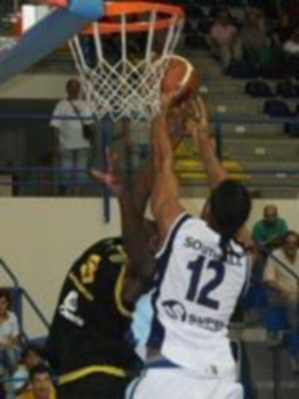 Jugador en acción durante un partido de baloncesto, intentando hacer un tiro a canasta.