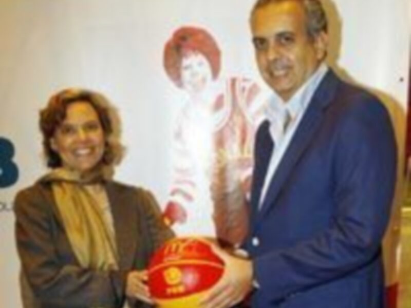 Dos personas posan con una imagen de una figura de mujer y un balón de fútbol rojo.