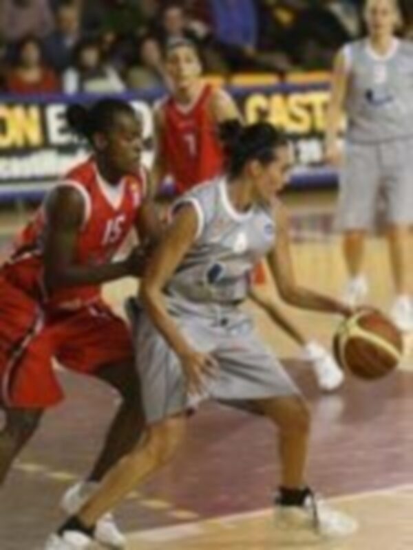 Un baloncesto en acción, con jugadores en el aro y un árbitro de fondo.