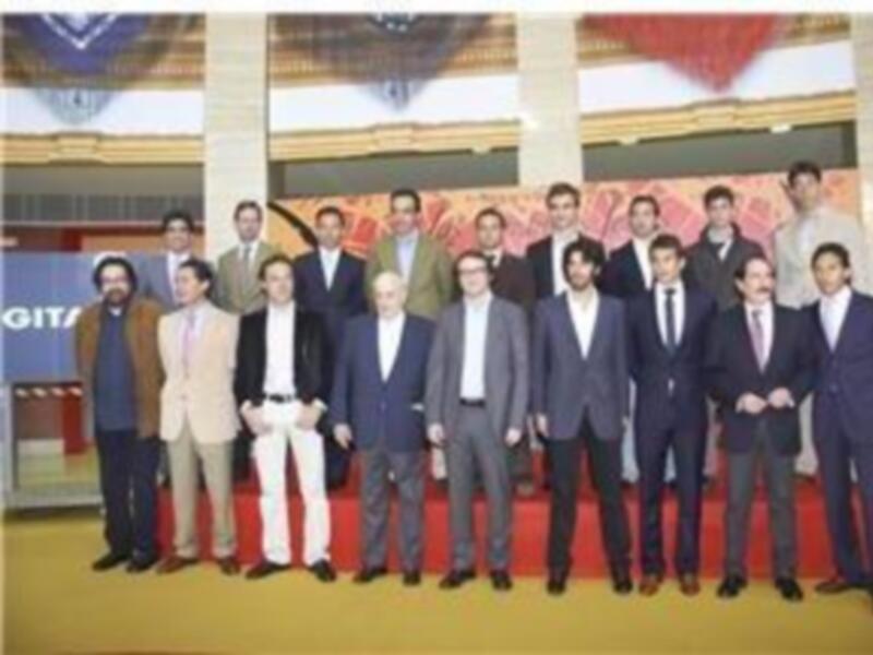 Un grupo de personas en trajes formales posa para una foto en un entorno formal con un fondo decorativo y una alfombra roja.
