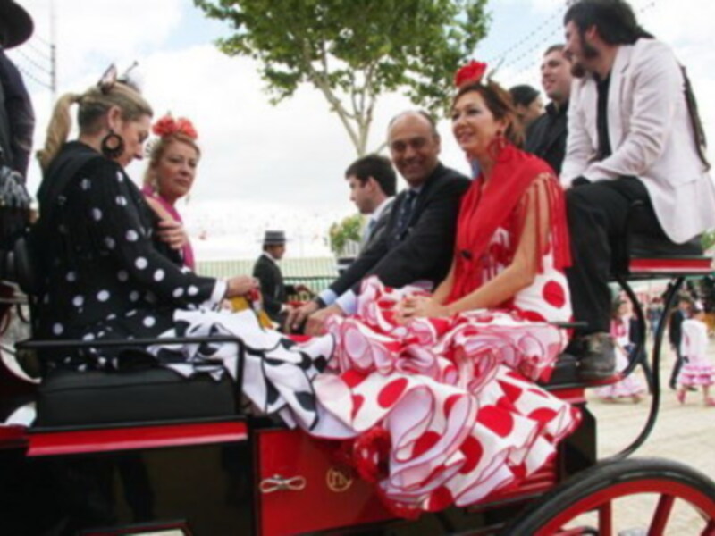 Fiesta española: damas en trajes tradicionales viajan en un carruaje durante una celebración.