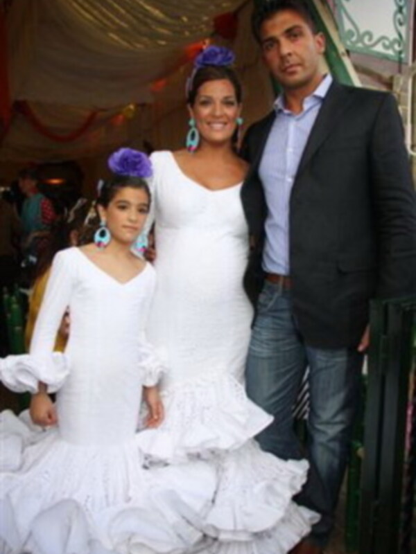 Familia celebrando en trajes típicos de España, con vestido blanco y flores en el cabello.