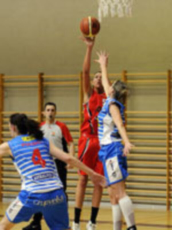 Jugadores de baloncesto en acción durante un partido en una cancha cubierta.