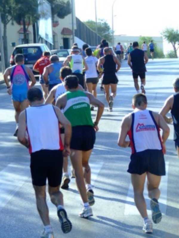 Corredores participan en una carrera de maratón urbana bajo el sol.