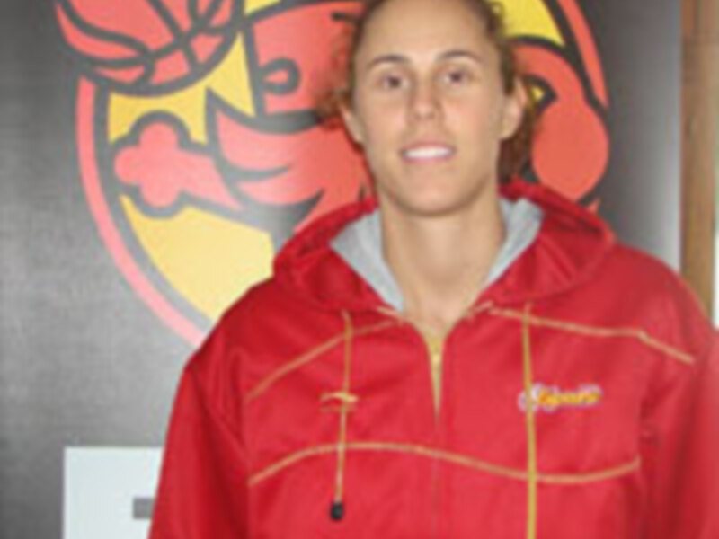 Joven en chaqueta roja con logo deportivo en el fondo.