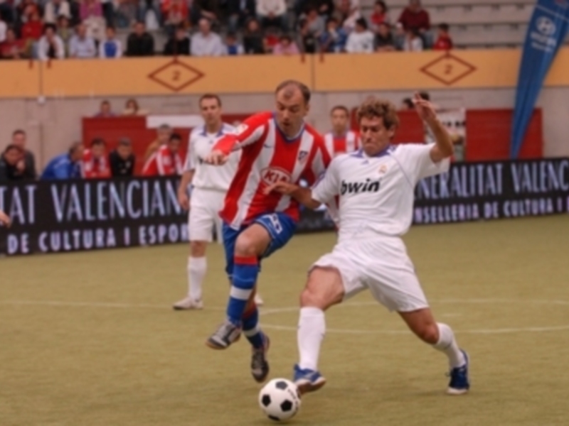 Jugadores en acción durante un partido de fútbol en un estadio con público.