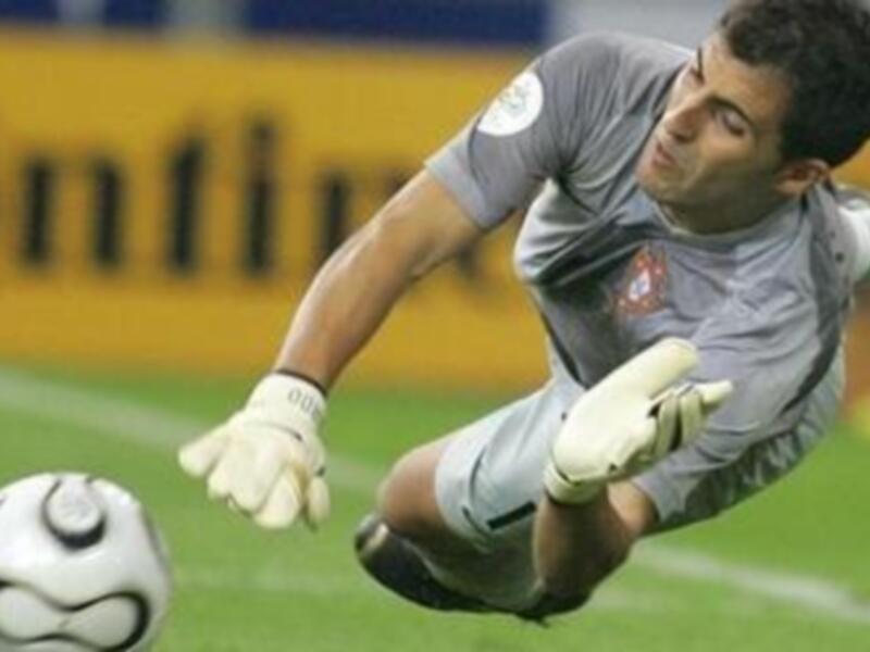 Un portero realiza una salto para atrapar un balón durante un partido de fútbol.