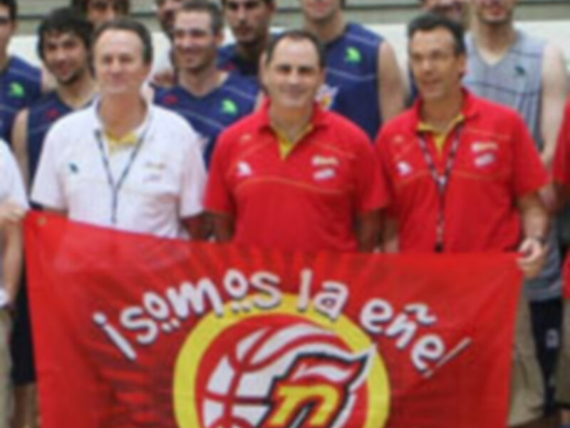 Equipo de baloncesto con bandera y entrenadores celebrando juntos.
