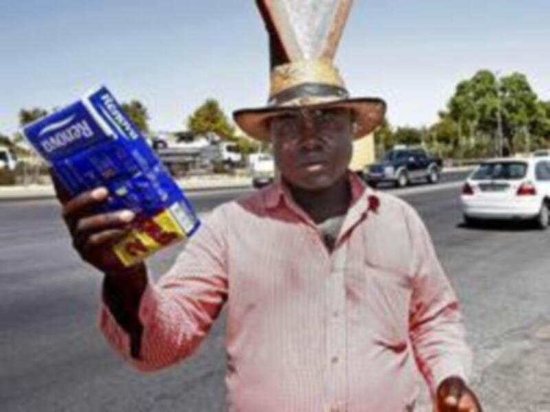 Un hombre con un sombrero de conejo y una camisa rosa sostiene una bolsa de chips de caramelo en una calle.