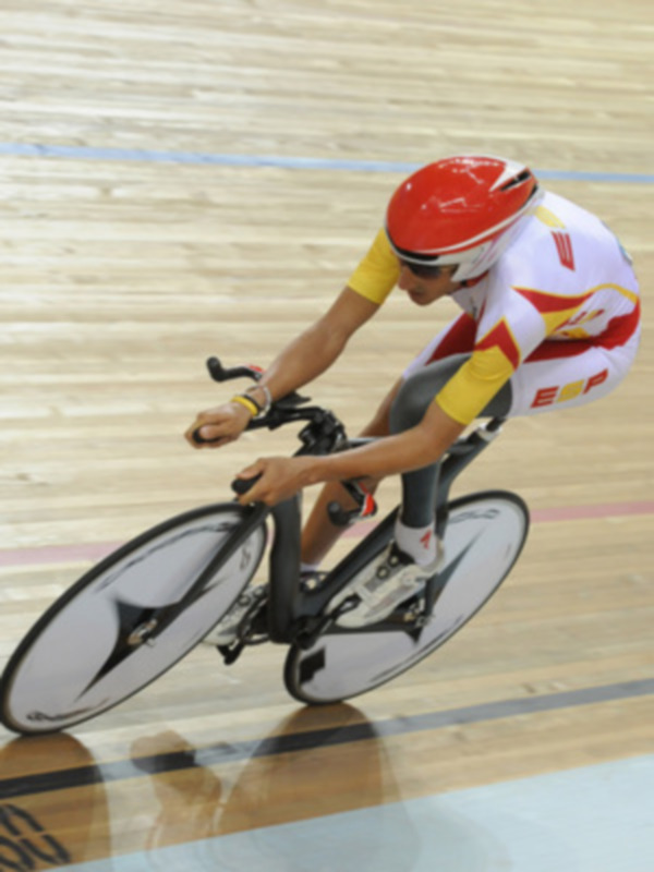 Atleta en bicicleta de pista en acción durante una competición de ciclismo indoor.