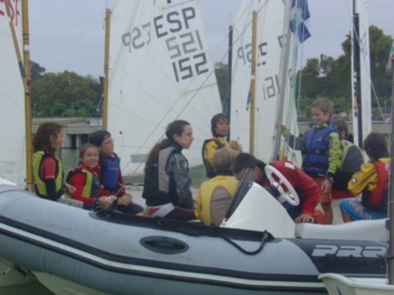 Grupo de jóvenes aprendiendo a navegar en un velero en un día nublado.