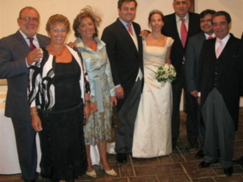 Familia y amigos celebran un matrimonio con una foto grupal en trajes y vestidos de novia.