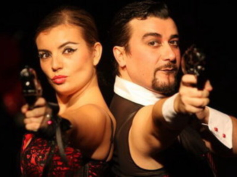 Una pareja en una escena de acción, con pistolas en la mano.
