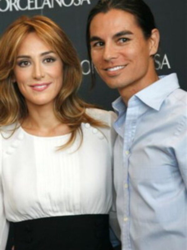 Dos personas sonrientes, una con cabello largo y ondulado de color claro y la otra con cabello largo y lacio, ambos vestidos formalmente.