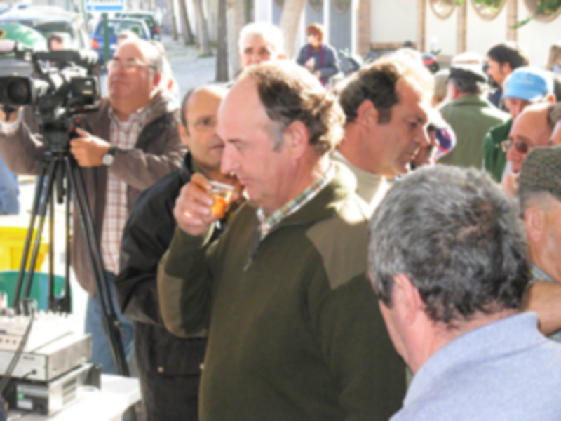 Un hombre toma una copa de vino mientras otros observan, en un ambiente festivo con decoración navideña.