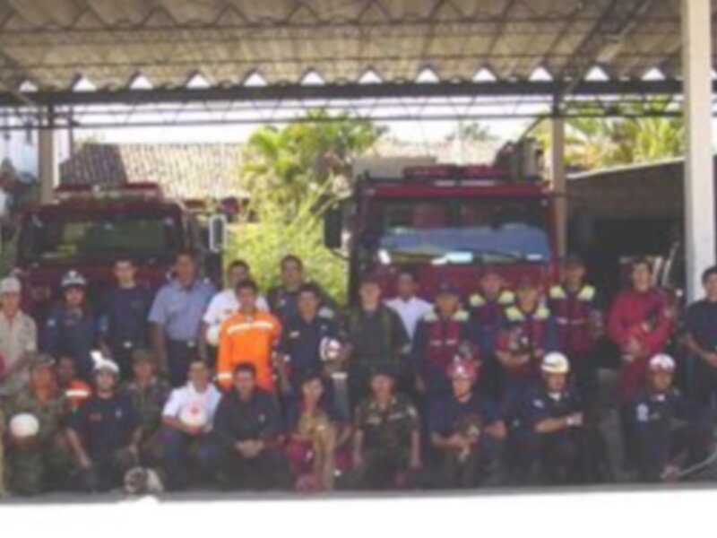 Grupo de bomberos y perros posando en un cuartel de bomberos.