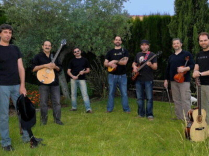 Grupo musical posando al aire libre con instrumentos de cuerda.