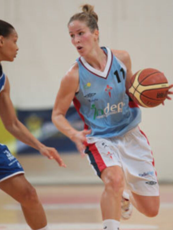 Dos jugadoras de baloncesto en acción durante un partido, una con el número 11 y la otra con el número 2, en un estadio deportivo con una pista de baloncesto.