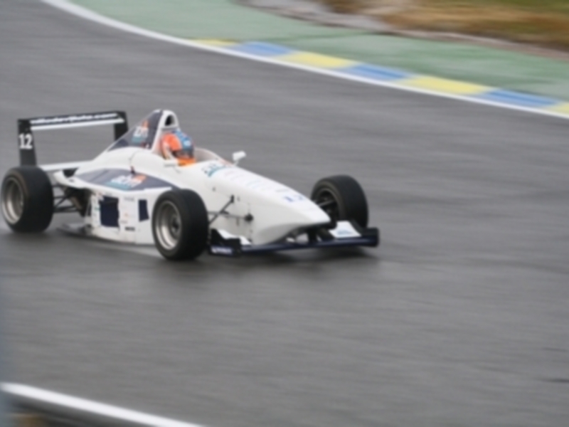 Un monoplaza de Fórmula 3 en acción durante una carrera en una pista de circuito.