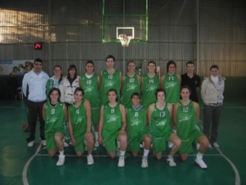Equipo de baloncesto femenino en uniforme verde posando para una foto en una cancha de baloncesto.