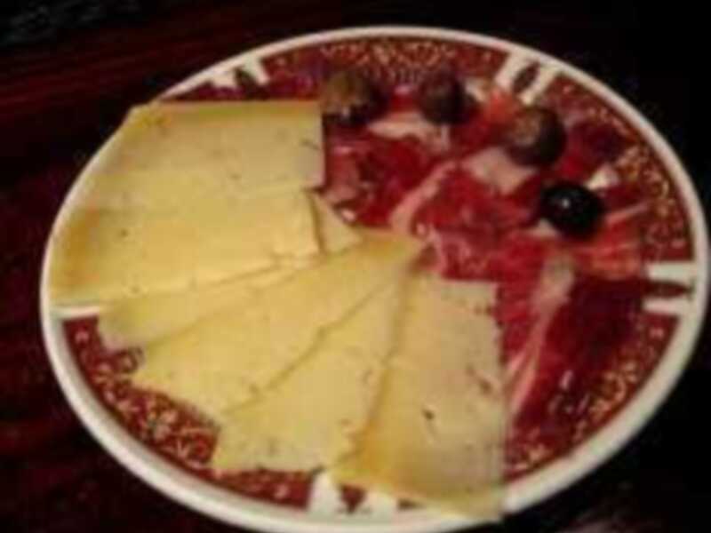 Plato de embutidos y queso con aceitunas, perfecto para una degustación de tapas.