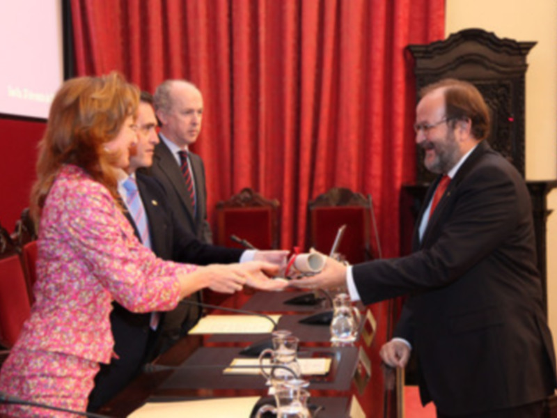 Un momento de intercambio formal en una reunión oficial, con dos personas intercambiando documentos.