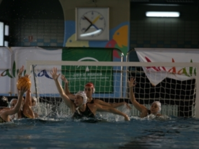 Jugadoras de waterpolo en acción durante un partido, luchando por el balón en la piscina.