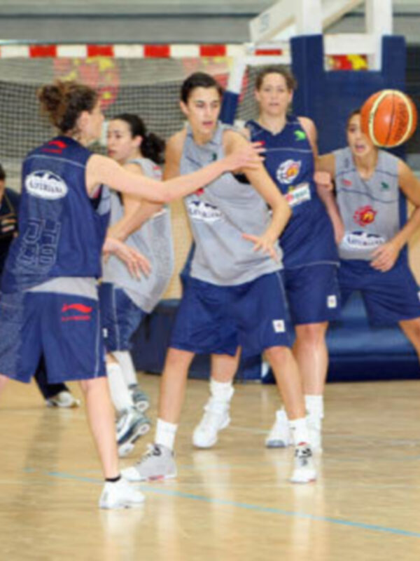 Jugadoras de baloncesto en acción durante un entrenamiento en un pabellón deportivo.
