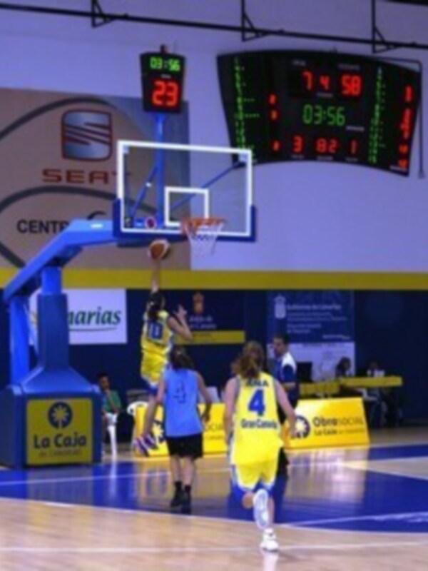 Un jugador de baloncesto en acción durante un partido, con el marcador electrónico mostrando 74-50 y el tiempo en juego.